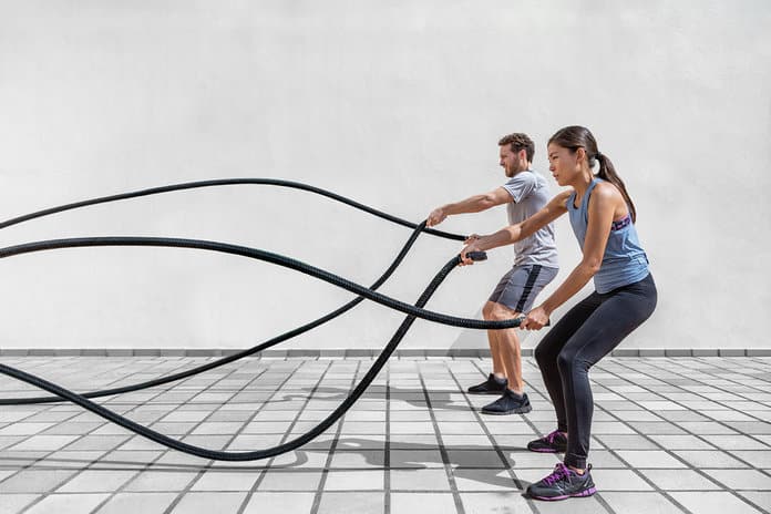 man and women using battle ropes