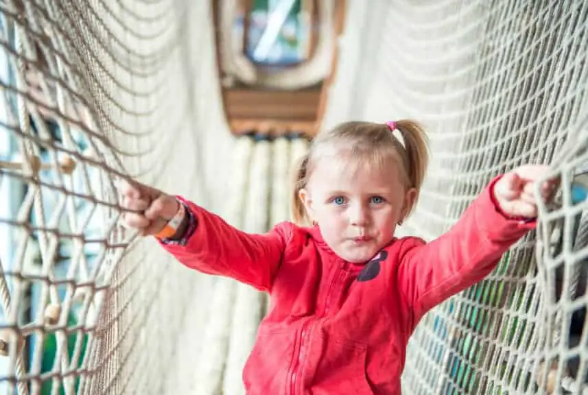 toddler climbing through rope tunnel bridge